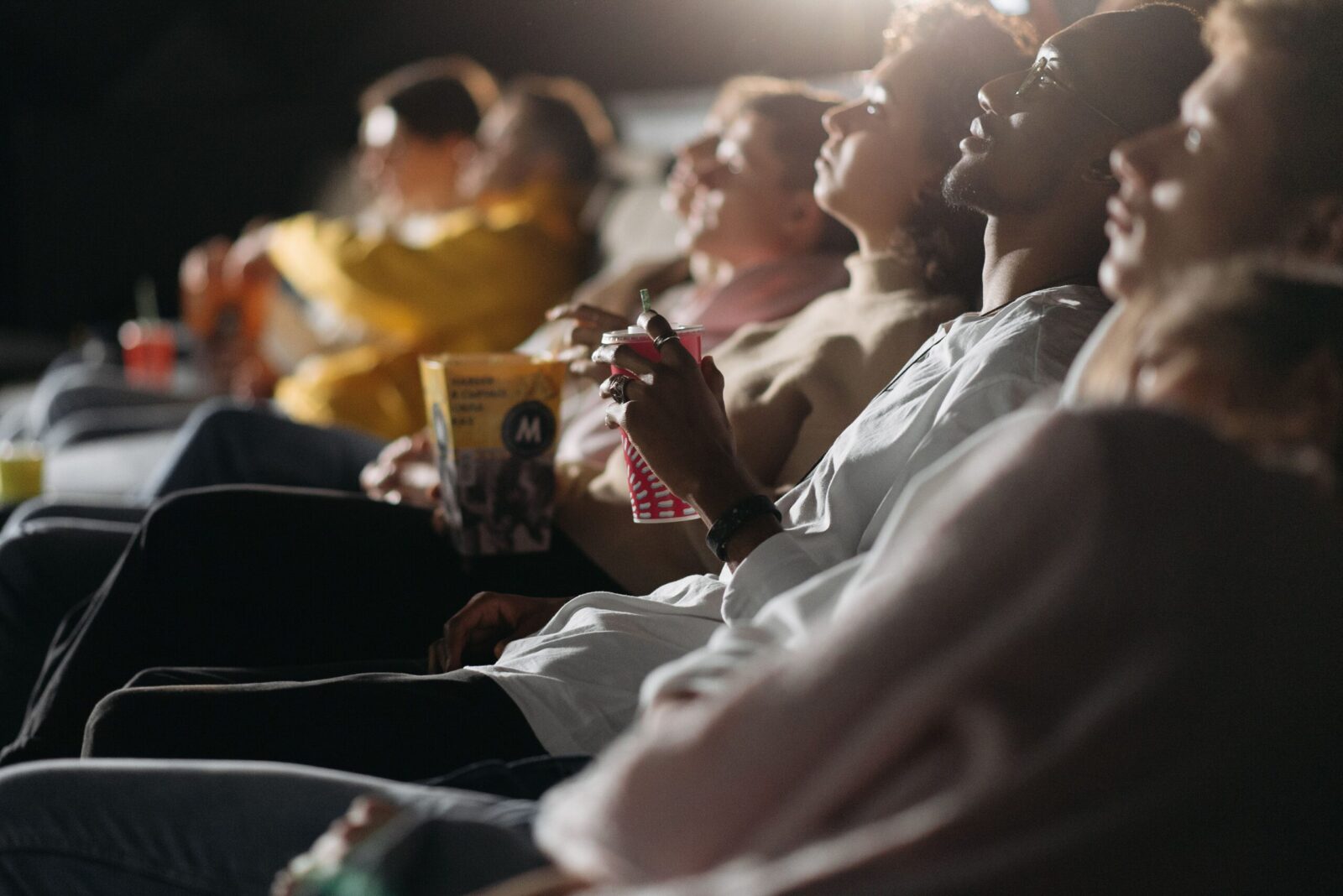 Group of friends watching a film in a cinema, sharing a fun movie night experience.